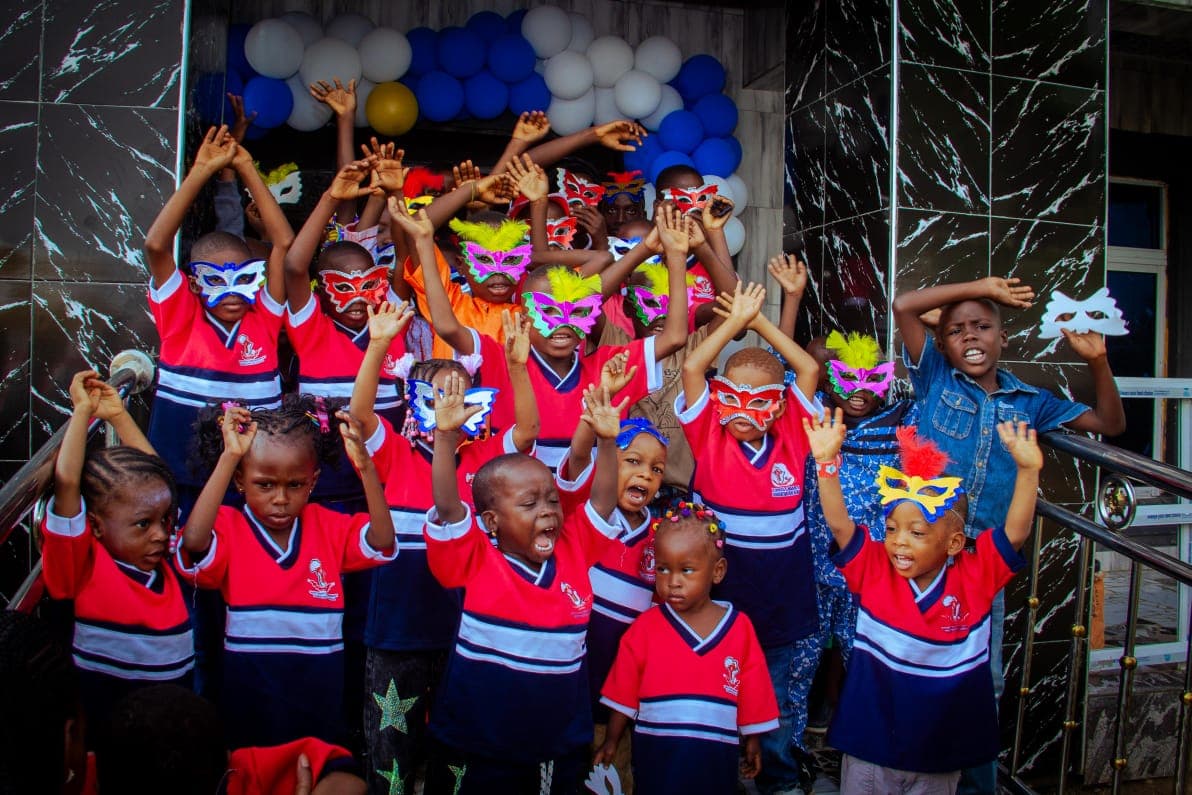 A group of children in school uniform raising their hands and celebrating at a Foundation event