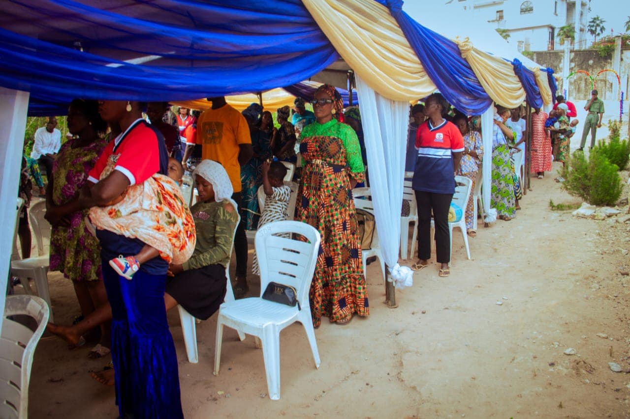 Members of a community gathered under a decorated canopy at a Foundation outreach