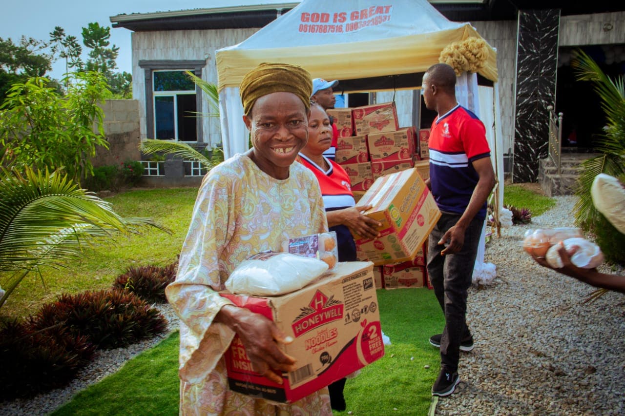 A woman smiling as she carries a box of food supplies received at a Foundation outreach